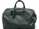 the large green duffel bag is sitting on a white surface