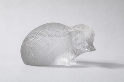 une figurine en verre représentant un éléphant posée sur une surface blanche
