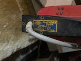 a red and black machine with a white cord attached to it