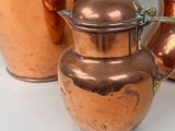 three copper pots sitting next to each other on a table