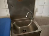 a blue trash can next to a sink in a public restroom