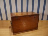 a small wooden box sitting on a table with a striped wall behind it