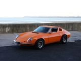 une voiture de sport orange garée sur le bord d'une route au bord de la mer