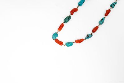 Collier de perles turquoise et corail sur fond blanc