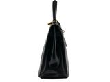a black handbag on a white background with a gold handle