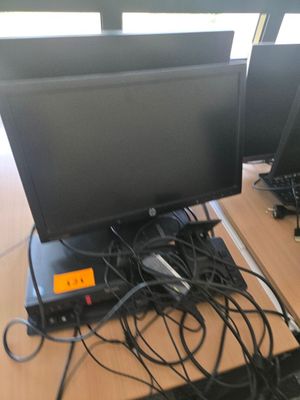 deux écrans d'ordinateur posés sur un bureau, entourés de câbles