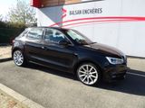La voiture noire est garée devant un immeuble orné d'une bande rouge.