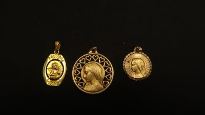 un gros plan sur trois pendentifs en or posés sur une surface noire