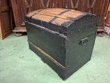 a black trunk with a wooden top sitting on a green floor