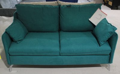 un canapé vert avec des coussins dessus, dans un magasin