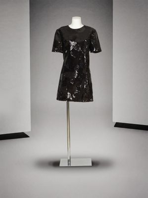une robe noire à paillettes posée sur un mannequin dans une pièce blanche