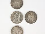 four different coins are arranged on a white surface
