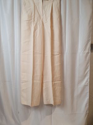 un pantalon beige suspendu à un rideau blanc devant un rideau blanc