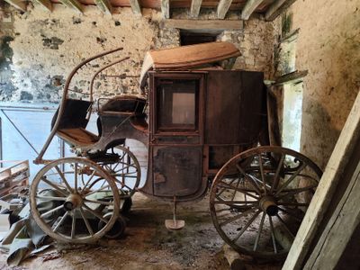 une voiture tirée par des chevaux, assise dans une pièce avec un mur en pierre