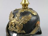 an old helmet with gold decoration on top of it on a white surface