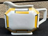 a yellow and white teapot sitting on a black table