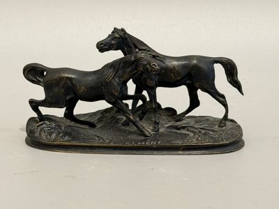 a bronze statue of two horses running on a hill
