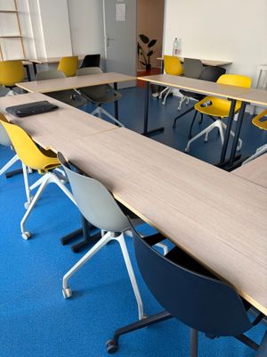 des tables et des chaises dans une pièce avec une moquette bleue et des chaises jaunes