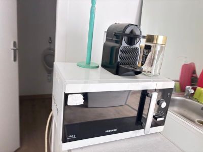 un micro-ondes sur lequel est posée une tasse, dans une cuisine