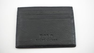 un gros plan d'un portefeuille en cuir noir posé sur une surface blanche