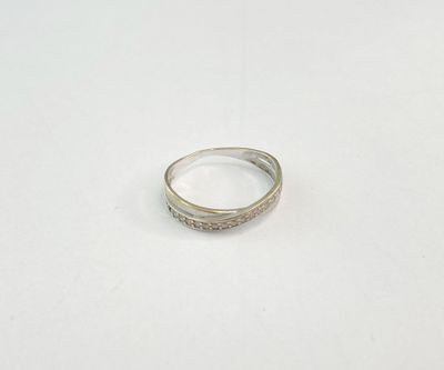 une bague en argent posée sur une surface blanche