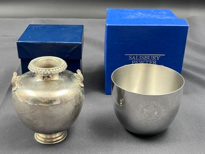 deux vases en argent posés à côté d'une boîte bleue sur une table