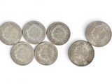 six different types of silver coins on a white surface