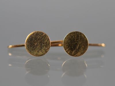 a pair of gold earrings on a white surface