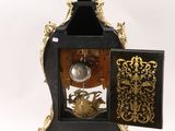 a black and gold clock sitting on a white surface