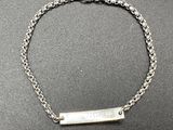 a close up of a silver chain bracelet with a bar on it