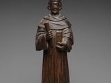 a wooden statue of a man holding a book in his hands