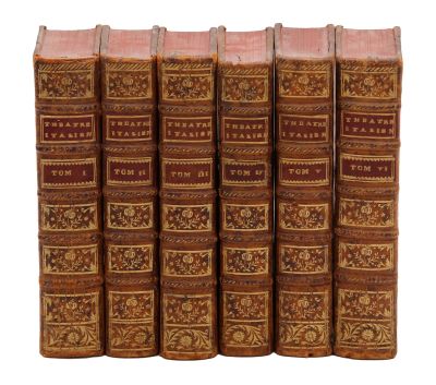 six vieux livres sont alignés sur une surface blanche