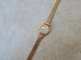 a close up of a gold watch on a white surface