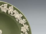 a green plate with white flowers and vines on it
