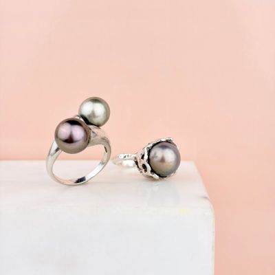 un gros plan sur une paire de bagues en perles posées sur un bloc de marbre