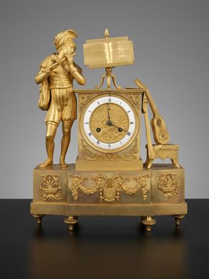 une horloge en or surmontée d'une statue représentant un homme tenant un livre