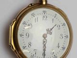 gros plan d'une montre de poche en or sur une surface blanche