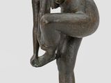 bronze statue of a woman bending over on a square base