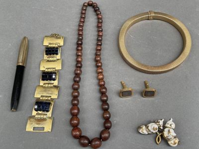 un collier, un bracelet, un stylo et d'autres objets posés sur une table