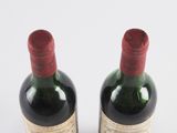 two bottles of wine sitting next to each other on a white surface