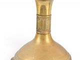 a gold vase that is sitting on a white surface