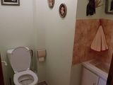une salle de bains équipée de toilettes, d'un lavabo, d'un miroir et de tableaux accrochés au mur