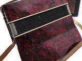 an image of a red accordion sitting on top of a brown bag
