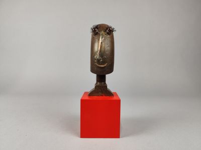 sculpture représentant une tête posée sur un socle rouge