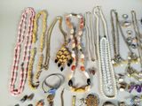 many different types of necklaces and bracelets on the table