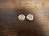 deux boutons en argent posés sur une table en bois