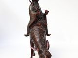 statue of a man riding a cow with a hat on