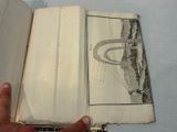 a hand holding an open book with a drawing on it