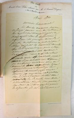 un livre ouvert sur lequel repose une feuille de papier, à côté d'une paire de ciseaux