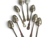six silver spoons are arranged in a circle on a white surface